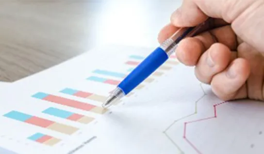 person holding a pen looking at a graph