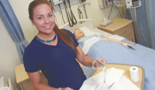 a nursing student smiles at the camera in a lab