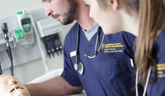 2 nursing students look at a medical dummy 
