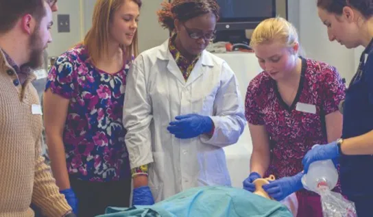 students and faculty gather around a hospital bed during a lesson
