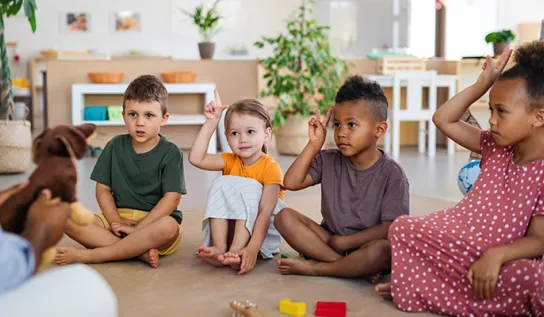 A group of diverse children seated on the floor at daycare.