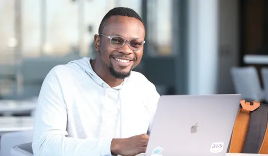 A Laurentian University student on his laptop and smiling.