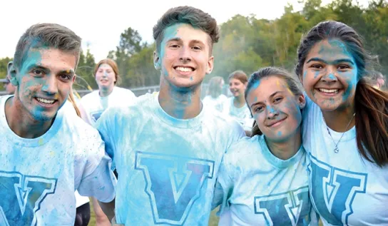 Laurentian University students arm-in-arm and smiling at the Orientation Colour Run.