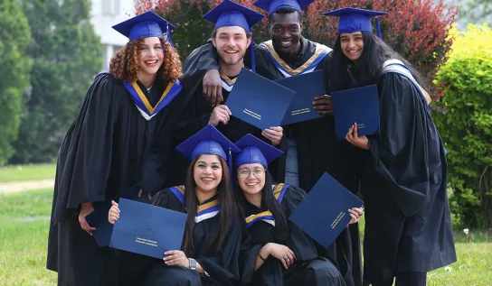 Laurentian University graduates posing outside with their degrees.