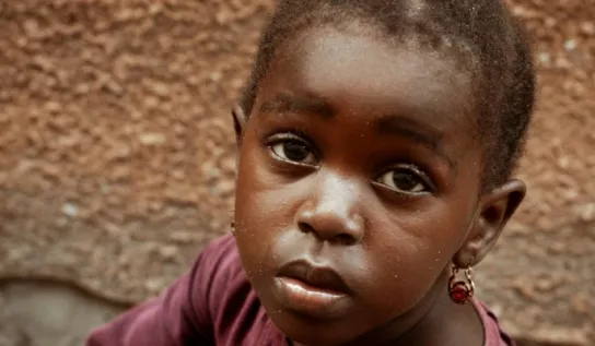 Female child on the ground looking up at the camera