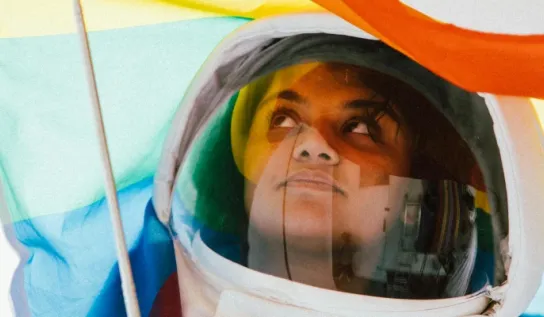 Female astronaut holding a pride flag