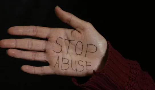 Womans hand with Stop Abuse written on the palm