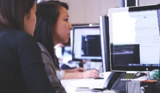 Two students are looking at desktop computer
