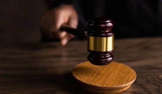 The scales of justice on a desk with a gavel in the foreground.