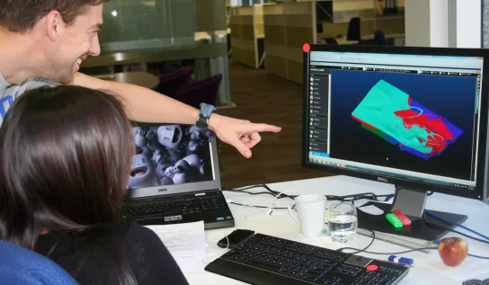 A student pointing at a computer desk 