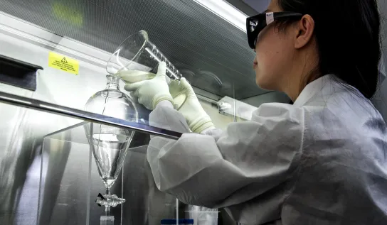 A student pouring clear liquid into a funnel