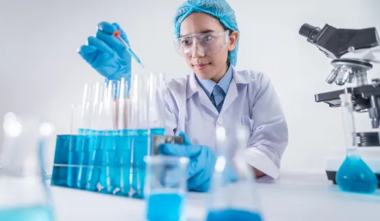 A student pipetting into a blue test tube in a laboratory