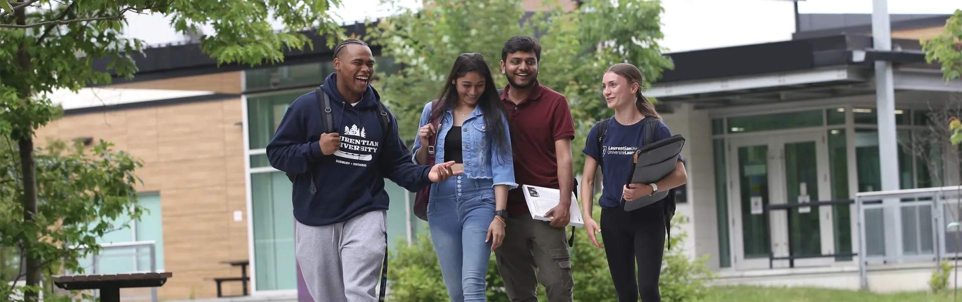 A group of Laurentian University students walking on campus with the Cliff Fielding building in the background.
