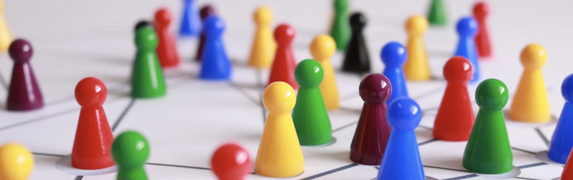 A close-up of multiple colourful board game pieces placed along a white game board.