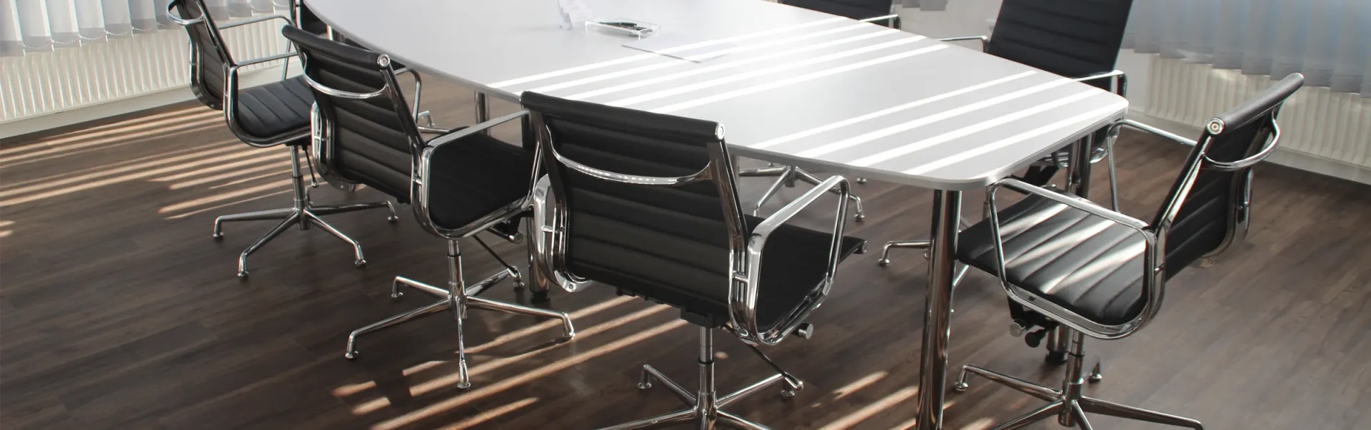 A white boardroom table with back chairs placed around it.