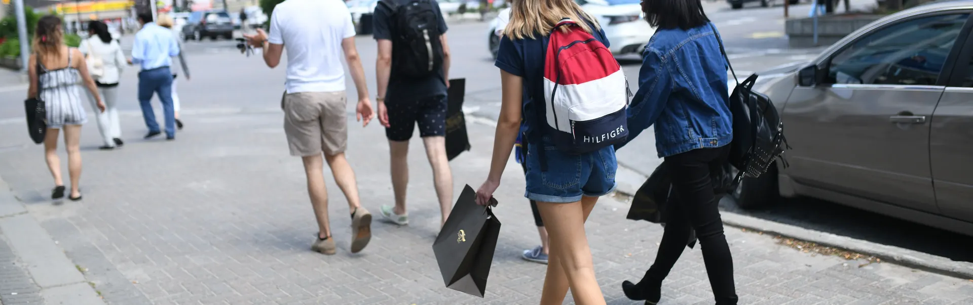 People walking on sidewalk downtown with shopping bag