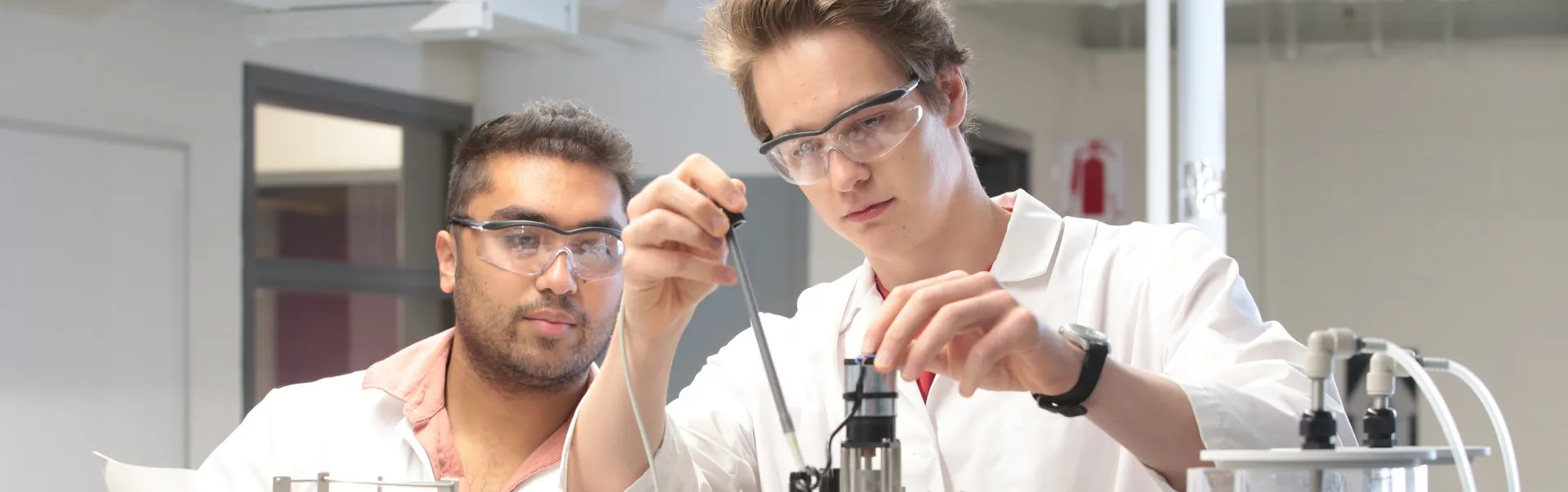 2 students in labcoats in a chemical lab