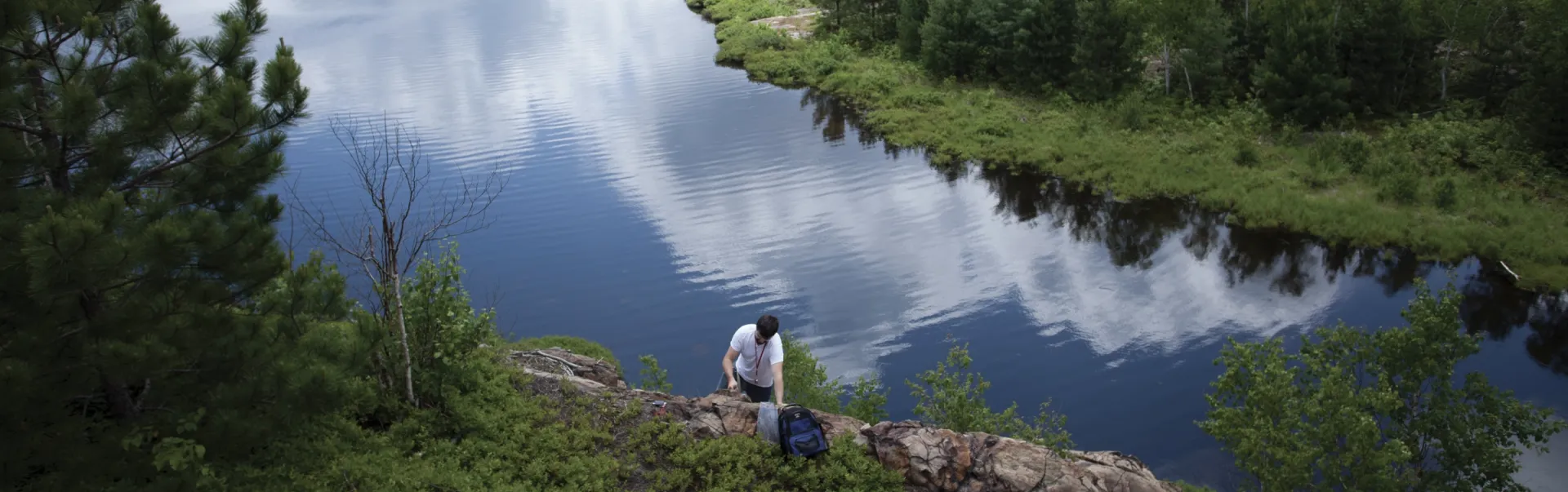An earth sciences student working in the field, with a lake in the background.