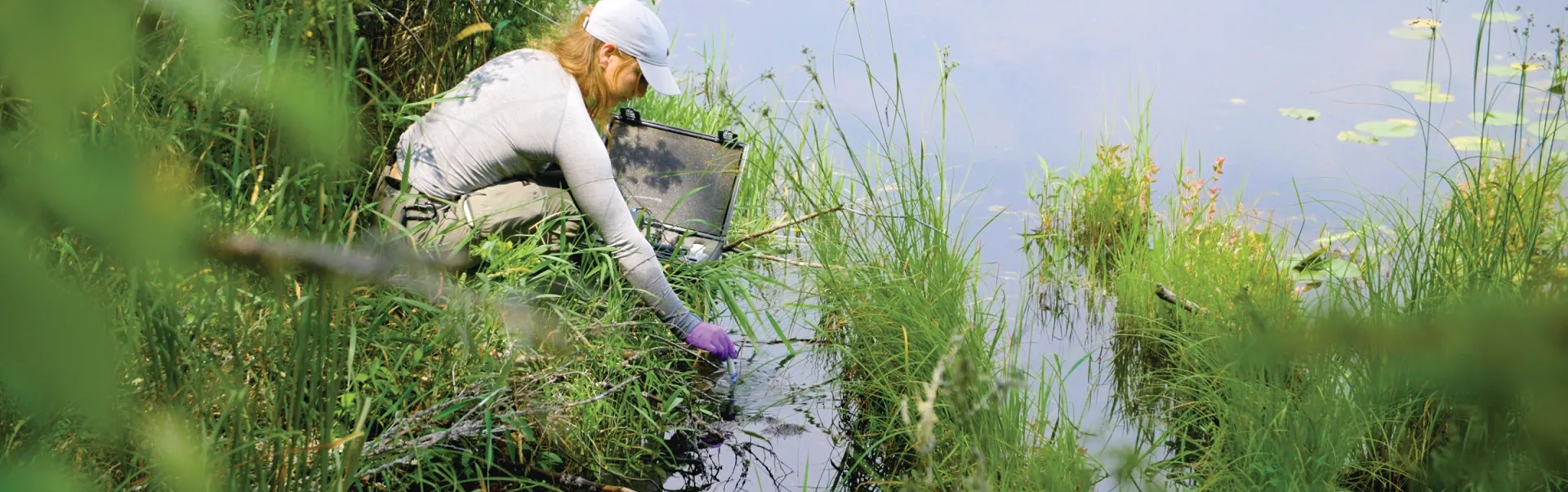 An Laurentian University Environmental Solutions student collecting water samples from a lake.