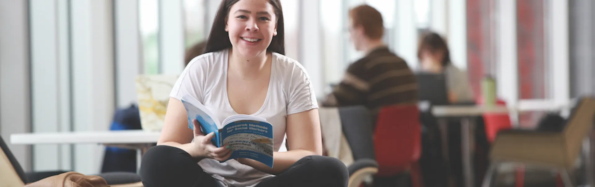 A student reviewing admissions booklet while looking at the camera