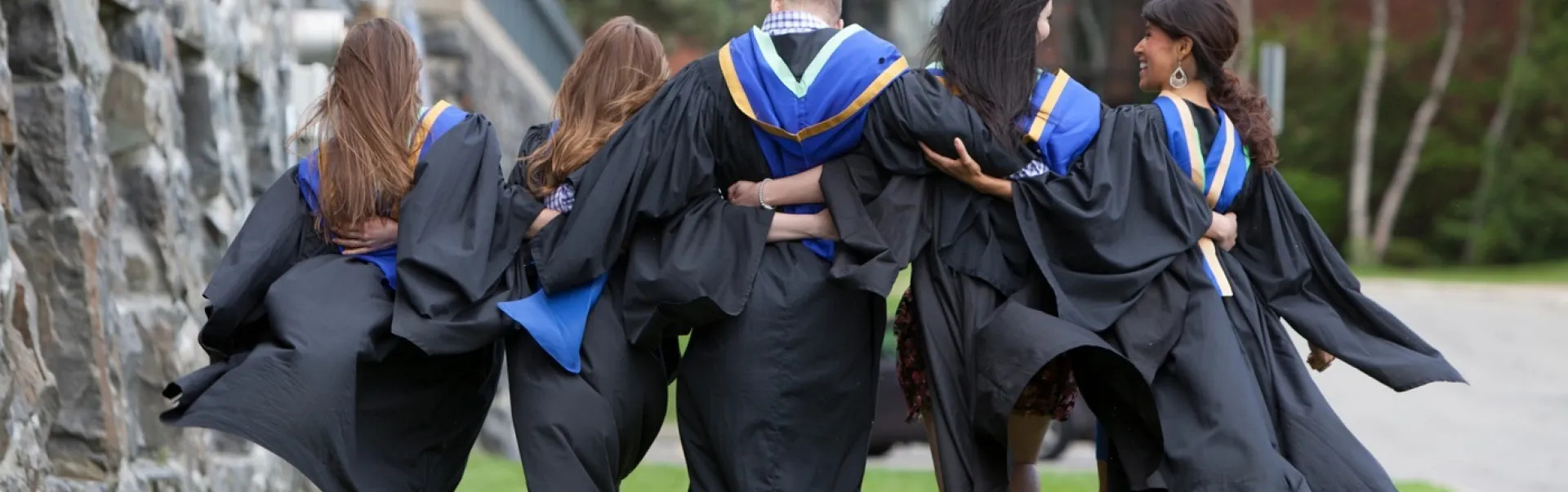 Graduates walking together with their arms around each other
