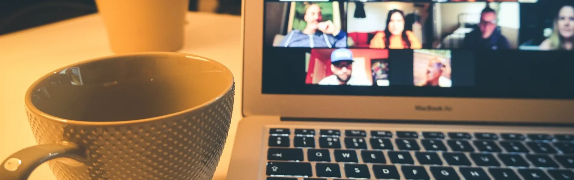A cup of coffee near a laptop on a desk 