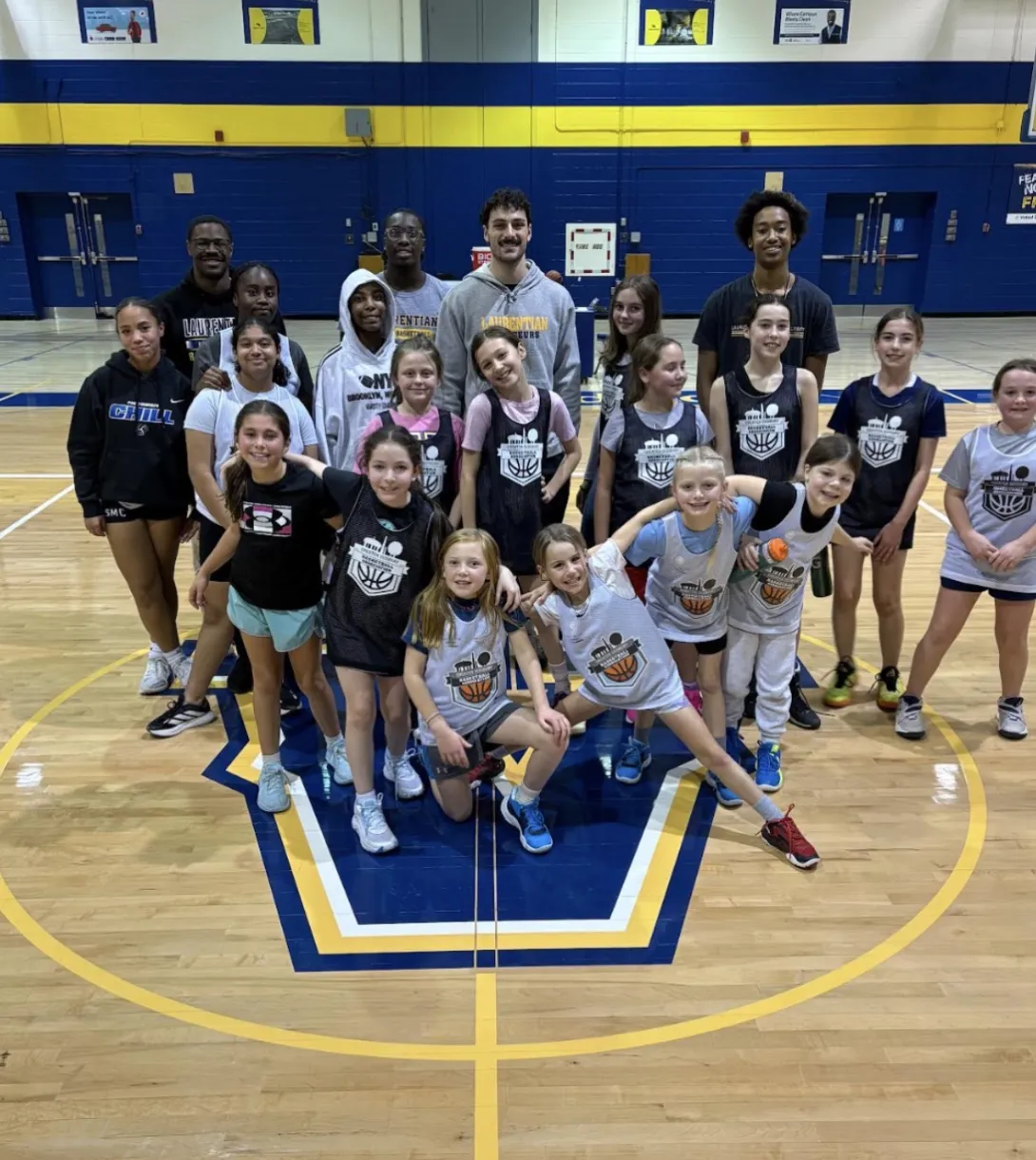 A group portrait on a basketball court featuring Evan Boudreau-Munro, several Laurentian University coaches, and a local youth house league team. 