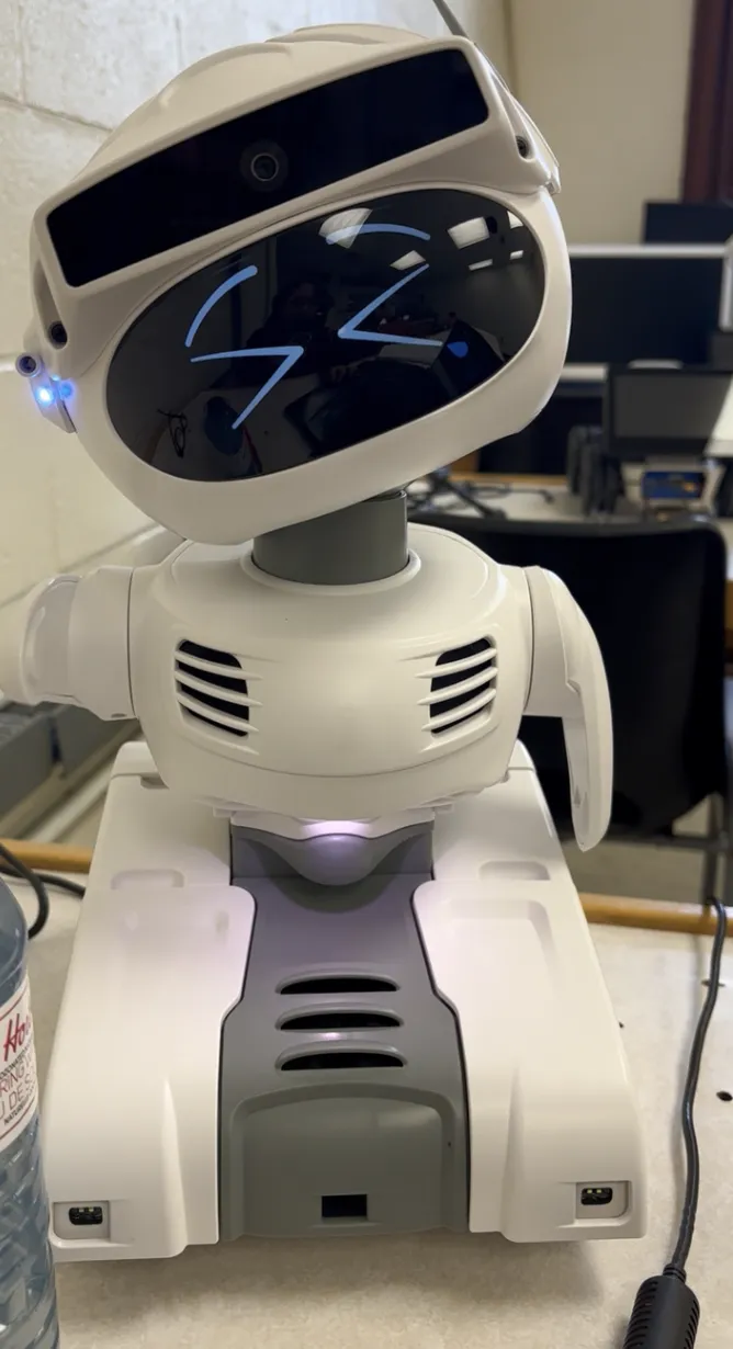 A close-up of the Misty II robot with its head tilted, displaying blue, stylized closed eyes on its screen to indicate tiredness. 