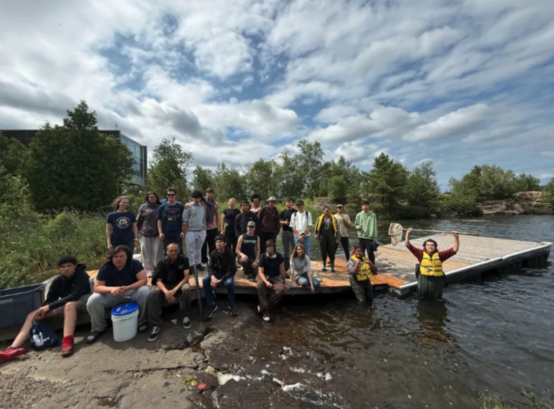 OYEP youth gathered on a wooden dock and in the water near the Vale Living with Lakes Centre during a field activity.
