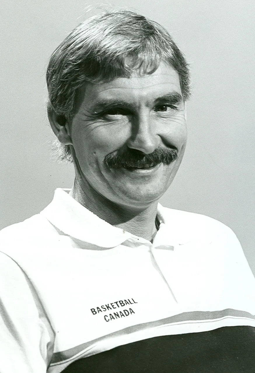 Black-and-white archival headshot portrait of former basketball coach Peter Campbell, smiling and wearing a polo shirt labeled "Basketball Canada".