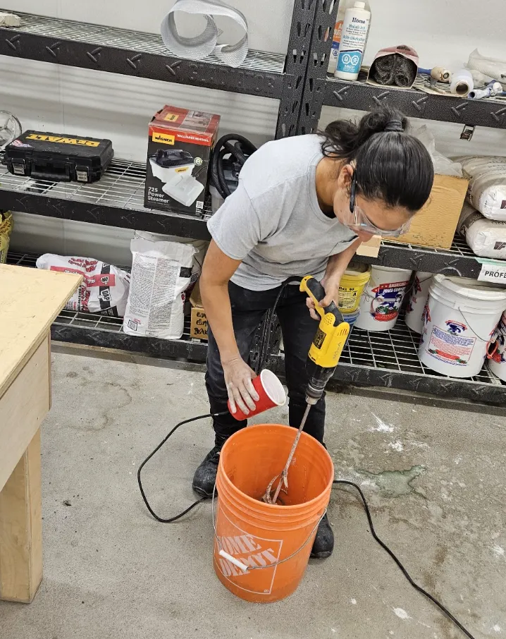 Michelle Zephyr uses a power mixer in a bucket while working on a project in the McEwen School of Architecture workshop.